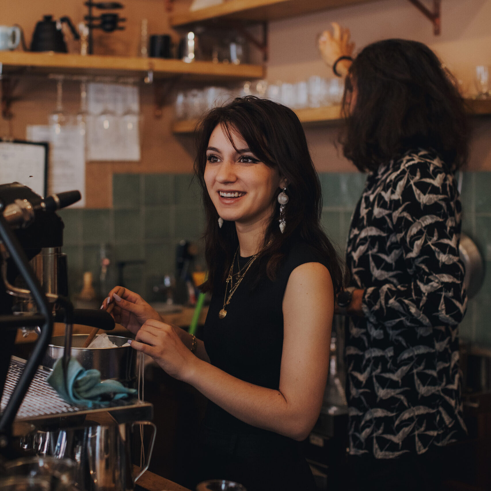 Bild zeigt eine Mitarbeiterin des Cafés, während sie einen Kunden berät.